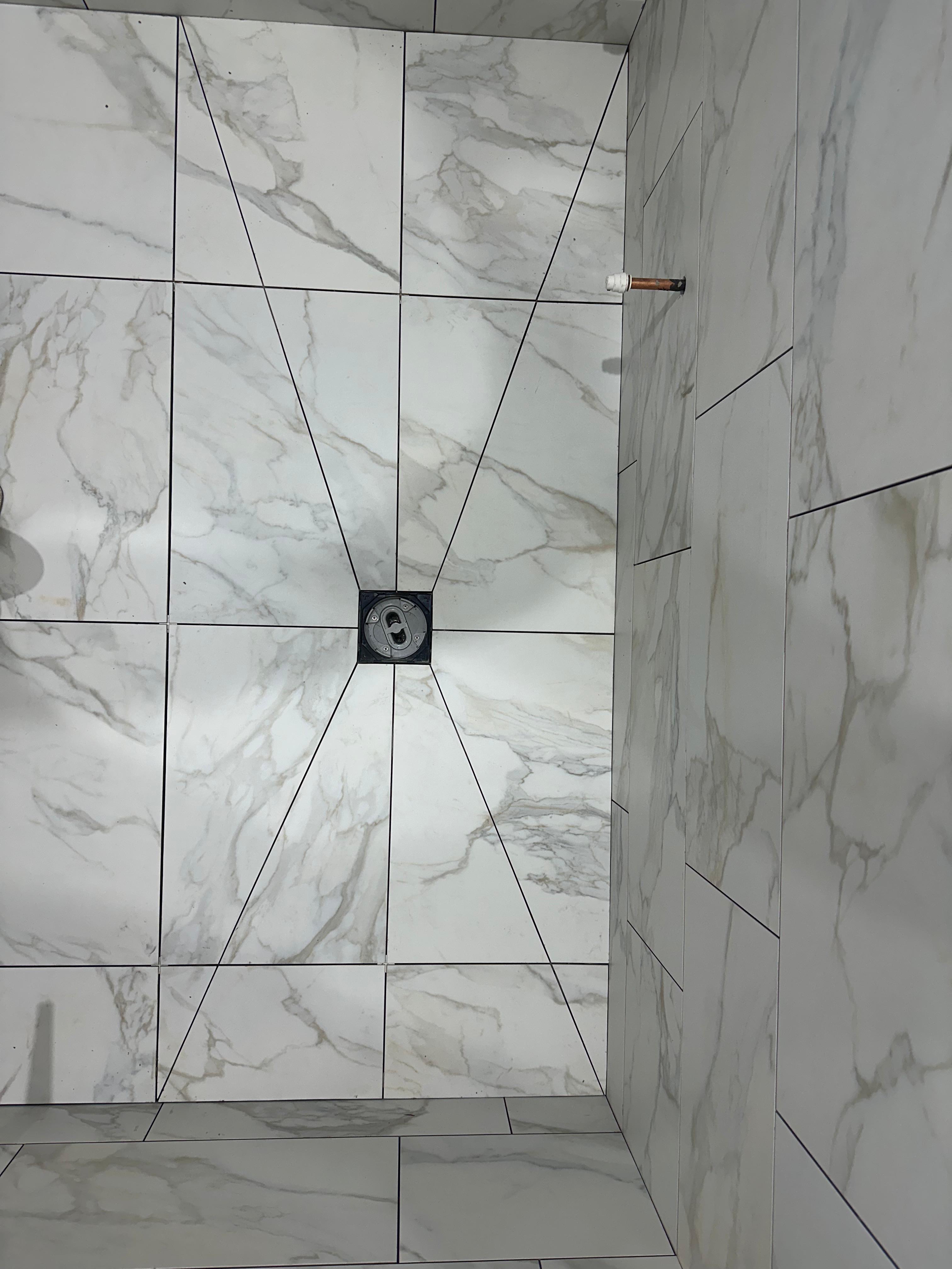 Calacatta marble wet room floor with graded tiles pointing to central drain, Beckenham — Bromley Tiler