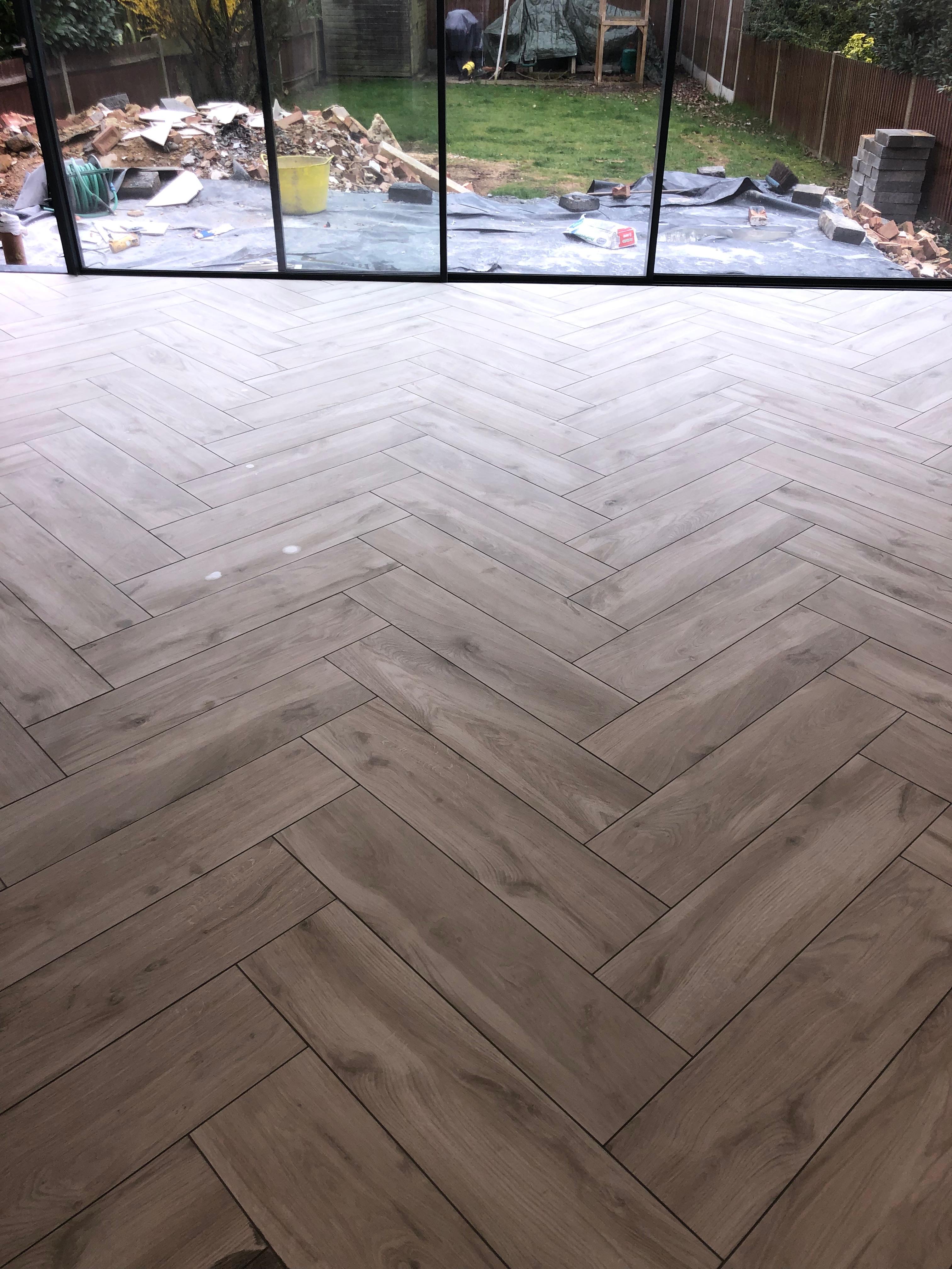 Grey wood herringbone floor tiles in open plan extension with bifold doors, Orpington — Bromley Tiler